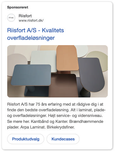 En række farverige og teksturerede laminatprøver er arrangeret som en vifte på en træoverflade. Dette reklamerer for Riisfort A/S, en leverandør af overfladeløsninger.